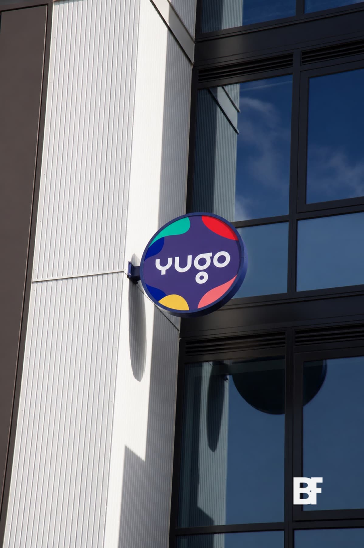 Colourful Yugo venue sign mounted on a modern facade